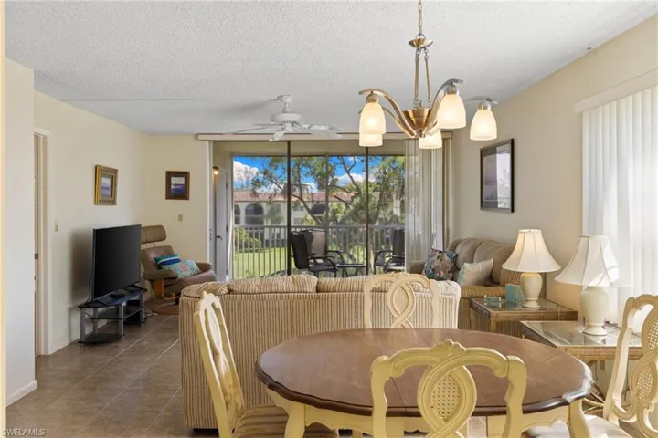 Dining room with a textured ceiling, tile patterned floors, a ceiling fan, and a chandelier