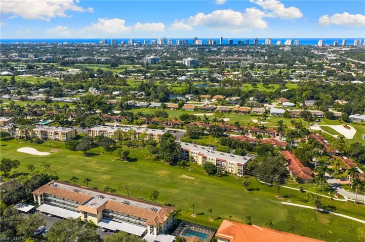 Drone / aerial view of skyline, a nearby body of water, and a golf club