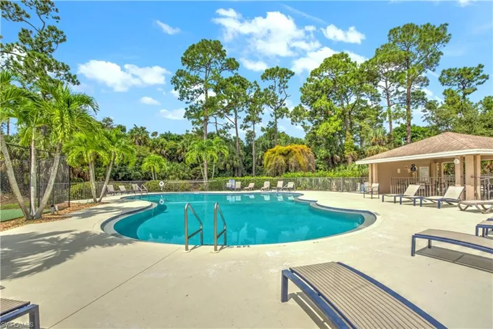 Community pool with a patio and view of wooded area