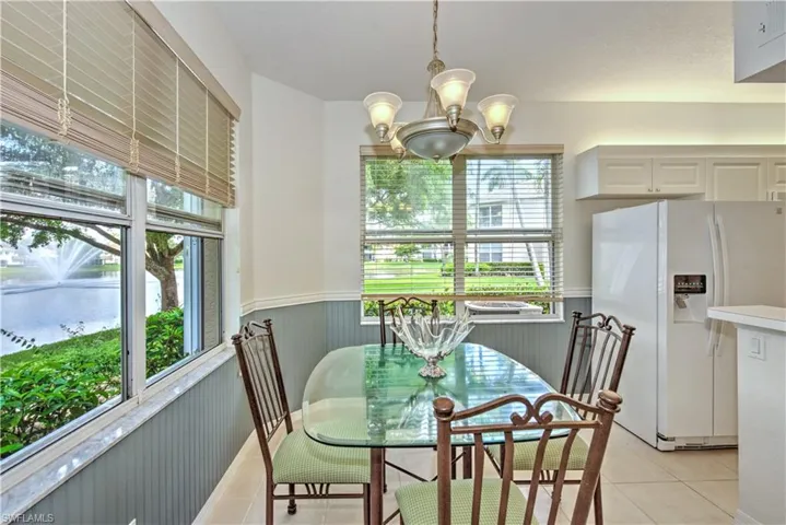 Dining area featuring a wainscoted wall, a water view, light tile patterned floors, and a chandelier