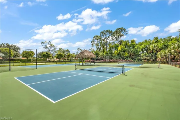 View of tennis court featuring a gazebo, community basketball court, and view of wooded area