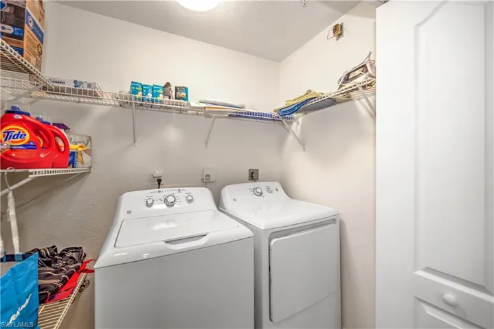 Laundry room featuring washer and dryer, a textured wall, and a textured ceiling