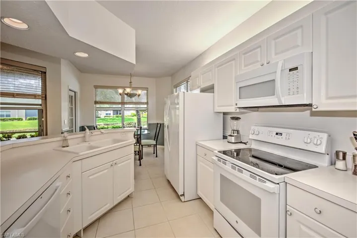 Kitchen with white appliances, white cabinetry, light countertops, a chandelier, and light tile patterned floors