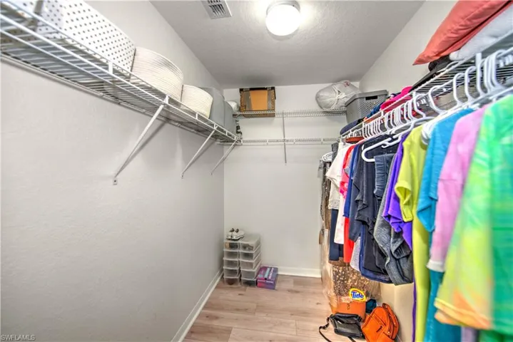 Walk in closet with light wood finished floors