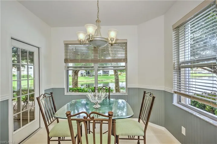 Tiled dining area with a wainscoted wall, a chandelier, and a water view