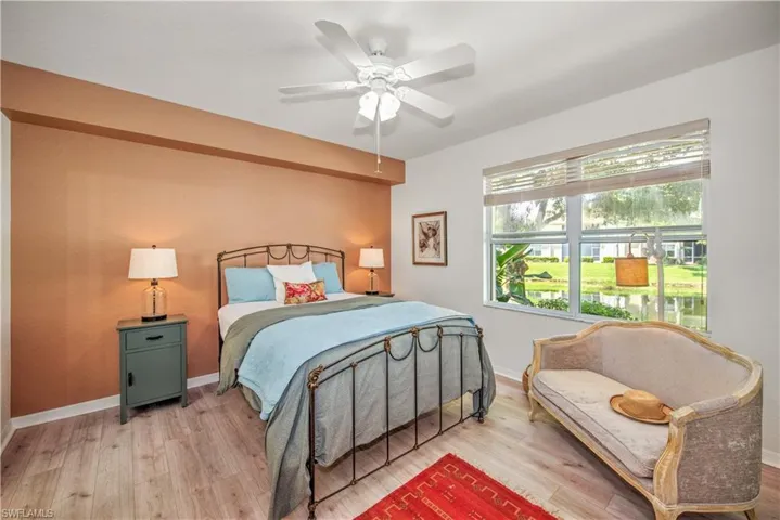 Bedroom with ceiling fan, wood finished floors, and a water view