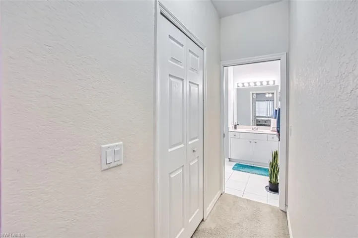 Hallway featuring a textured wall and light colored carpet