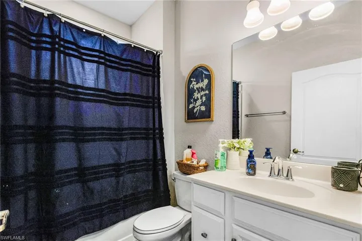 Full bath with vanity and a textured wall