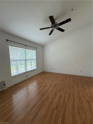 Unfurnished room with dark wood-type flooring and ceiling fan