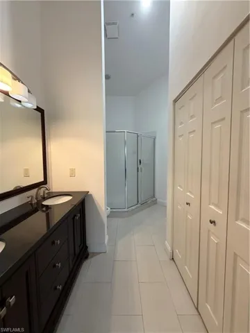 Bathroom with double vanity, a stall shower, and a closet