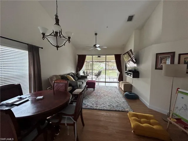 Dining room with lofted ceiling, dark wood finished floors, a ceiling fan, and a chandelier