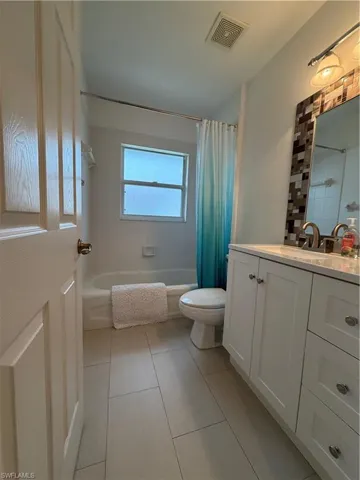 Bathroom featuring vanity and shower / bath combination with curtain