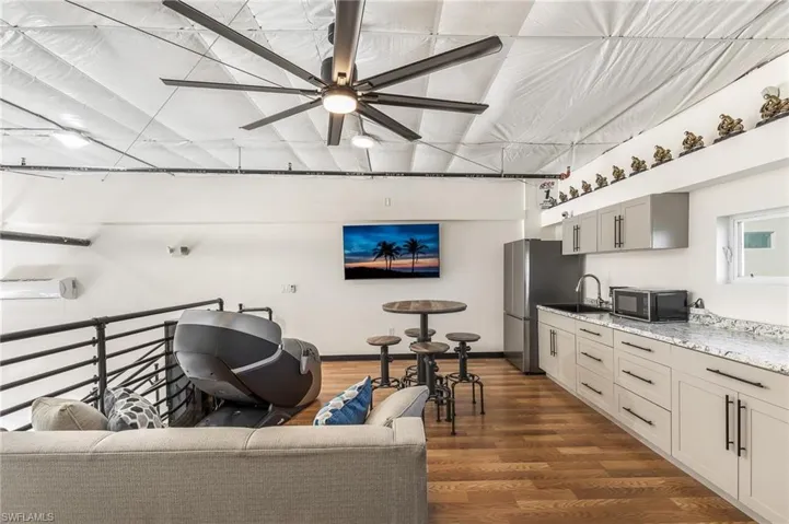Living room featuring a ceiling fan and dark wood-style floors
