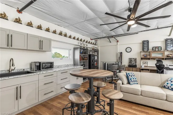 Kitchen featuring gray cabinetry, light wood finished floors, light stone counters, and open floor plan