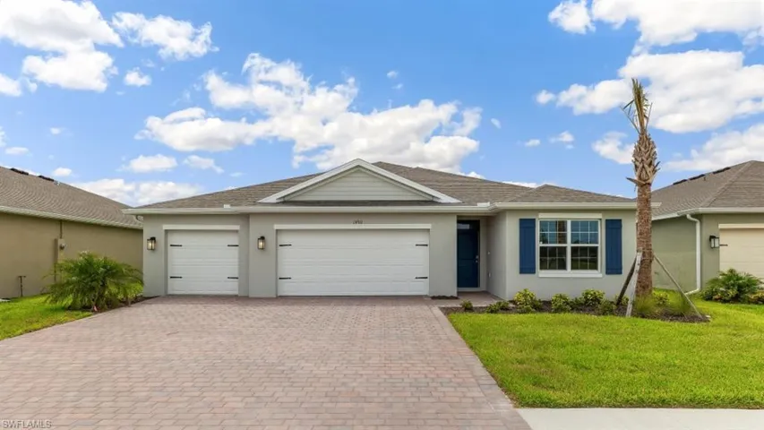 Ranch-style home with stucco siding, a front yard, decorative driveway, and a garage