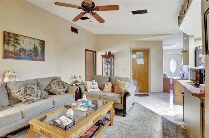 Tiled living room featuring vaulted ceiling and ceiling fan