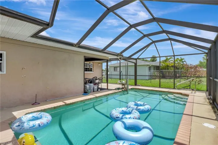 View of pool with glass enclosure, a patio area, and a yard