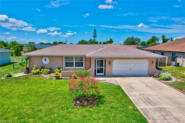 Ranch-style home with a garage, a front lawn, and central air condition unit