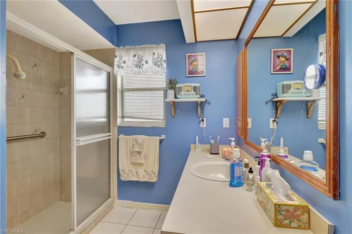 Bathroom with a shower with door, tile flooring, plenty of natural light, and vanity