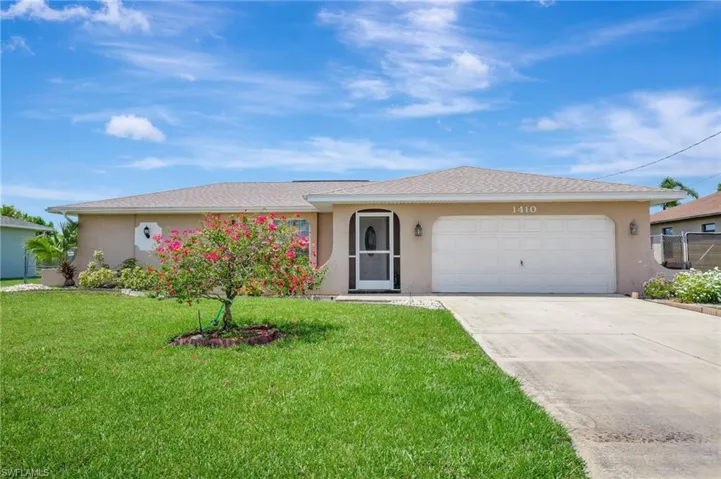 Single story home featuring a garage and a front lawn