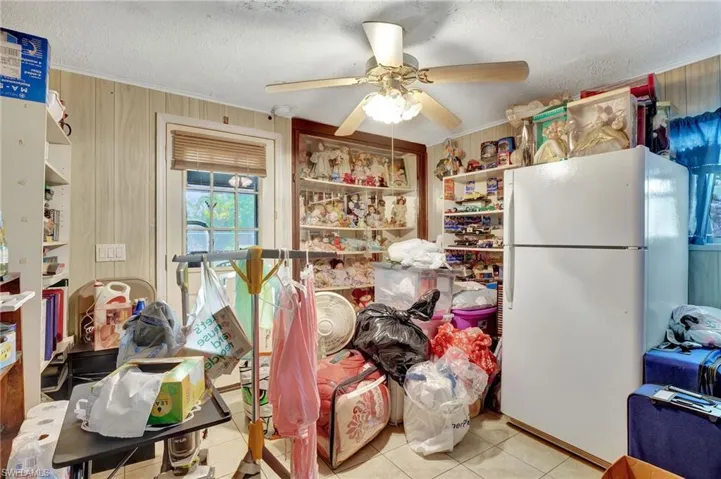 Kitchen with a textured ceiling, ceiling fan, white refrigerator, and light tile flooring