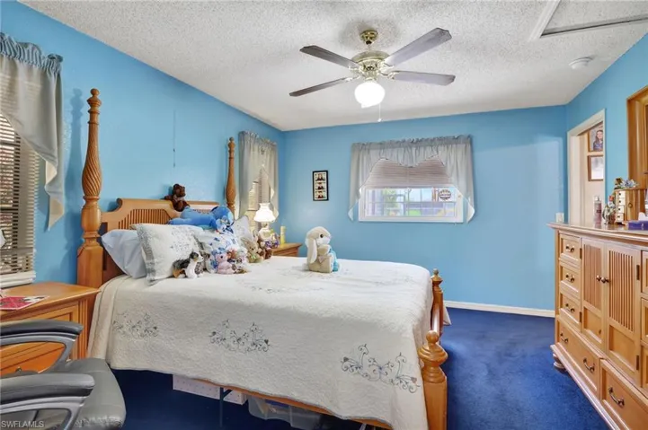 Bedroom featuring dark carpet, ceiling fan, and a textured ceiling