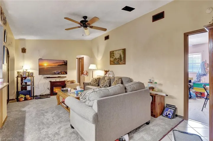 Living room with light carpet, ceiling fan, and vaulted ceiling