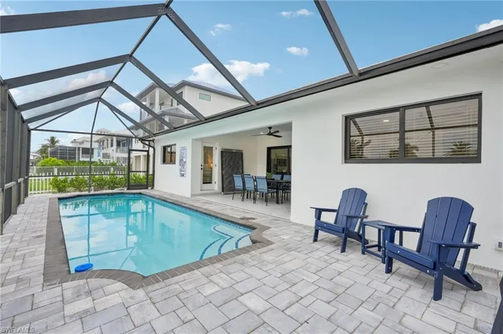 View of pool with a sunroom, a patio, glass enclosure, ceiling fan, and outdoor dining space