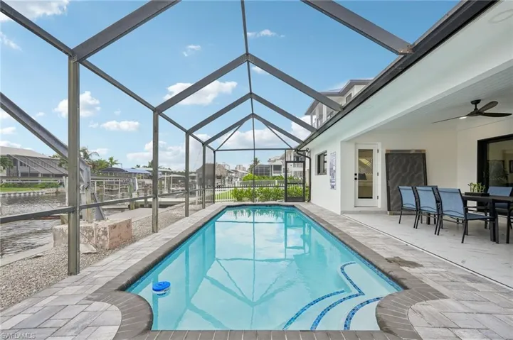 Outdoor pool featuring a sunroom, a patio area, a ceiling fan, a lanai, and a water view