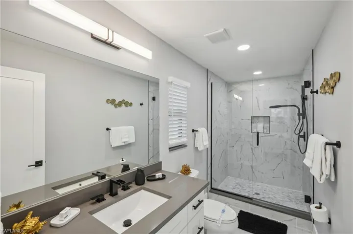 Full bathroom with a marble finish shower, vanity, and recessed lighting