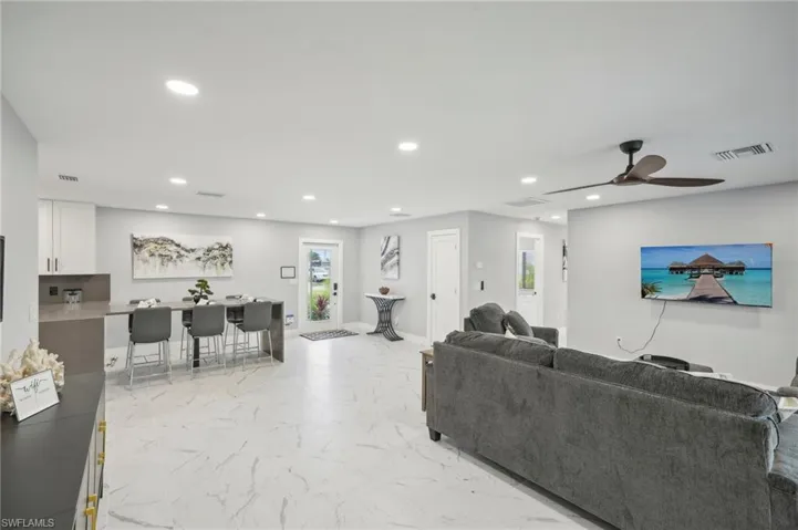 Living area featuring light marble finish floors, recessed lighting, and a ceiling fan