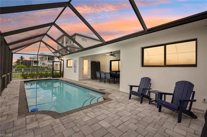 Pool at dusk with a sunroom, a lanai, a ceiling fan, and a patio