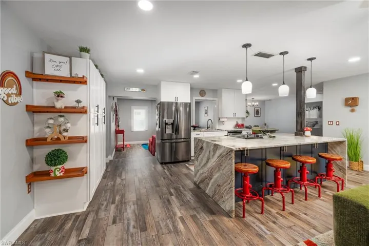 Kitchen featuring a kitchen breakfast bar, dark hardwood / wood-style flooring, white cabinets, light stone counters, and stainless steel fridge with ice dispenser