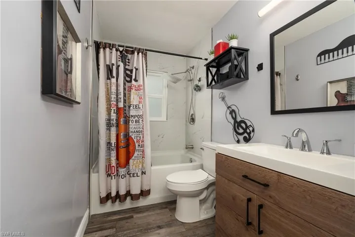Full bathroom featuring toilet, shower / bath combination with curtain, vanity, and wood-type flooring