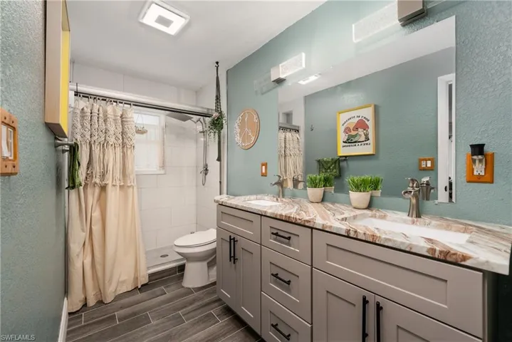 Bathroom with curtained shower, double vanity, and toilet