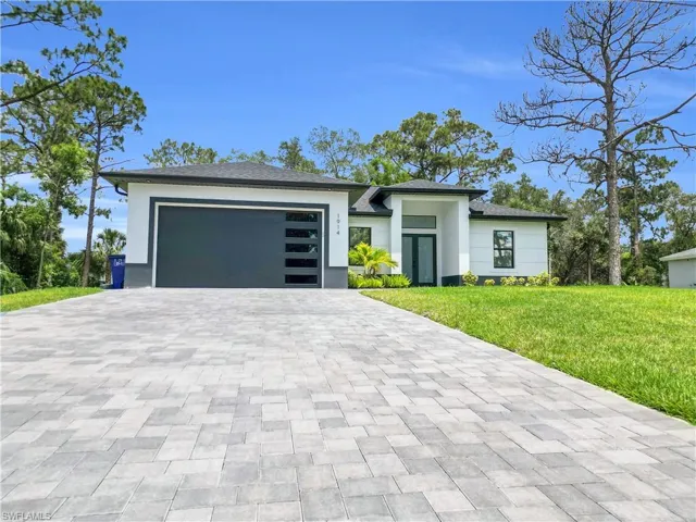 Prairie-style house featuring a front yard, an attached garage, decorative driveway, and stucco siding