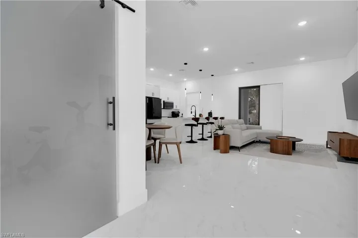 Living room featuring recessed lighting, a barn door, and light marble finish floors