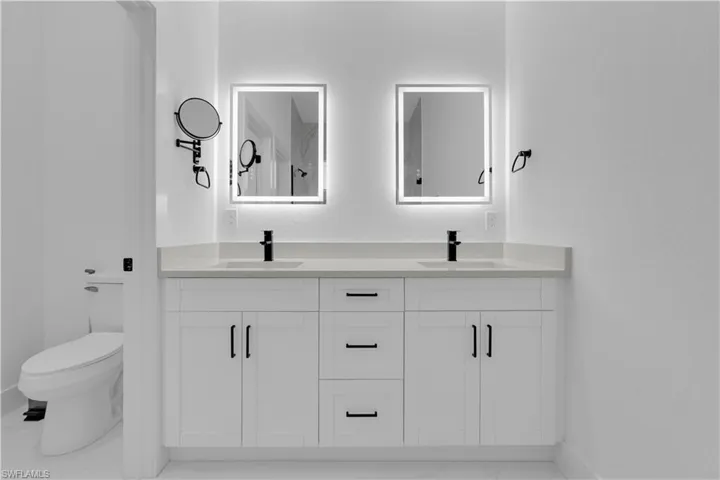 Bathroom with double vanity and light marble finish flooring