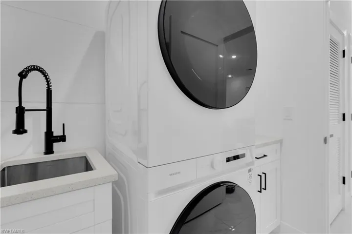 Laundry area featuring stacked washing machine and dryer and cabinet space