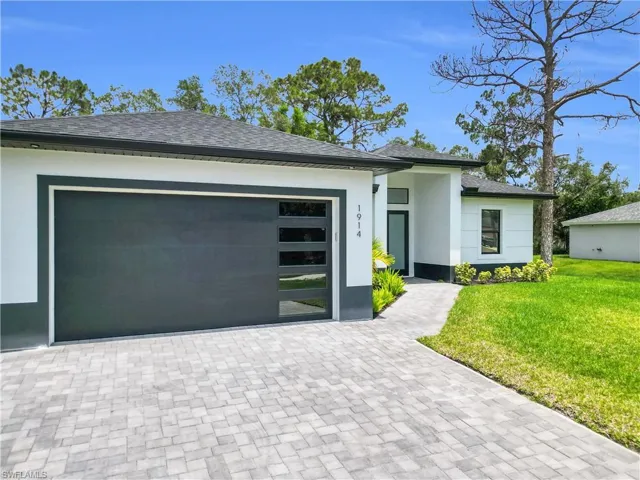 View of front of home with a front yard, decorative driveway, stucco siding, an attached garage, and roof with shingles