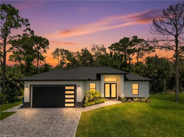 View of front facade featuring a front yard, decorative driveway, a garage, a shingled roof, and stucco siding