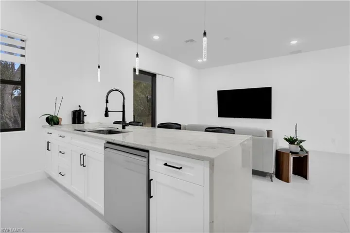 Kitchen featuring light stone counters, pendant lighting, dishwasher, white cabinetry, and recessed lighting