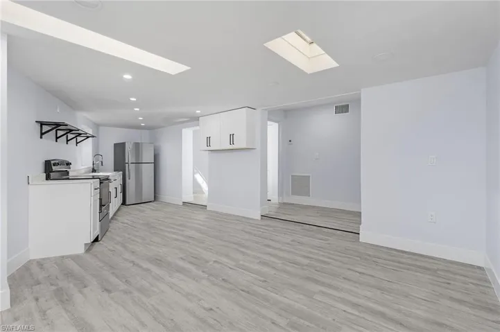 Kitchen with appliances with stainless steel finishes, a skylight, recessed lighting, light wood-style flooring, and white cabinets