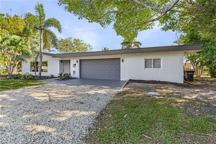 View of front facade with gravel driveway, a garage, and stucco siding