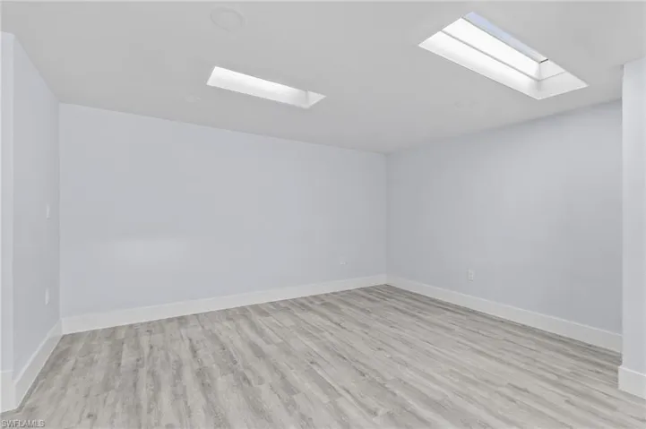 Unfurnished room with a skylight and wood finished floors