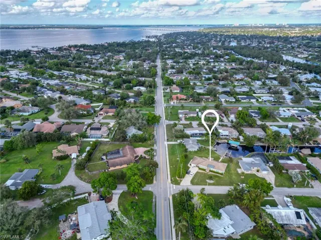 Aerial view of property and surrounding area featuring a nearby body of water and nearby suburban area