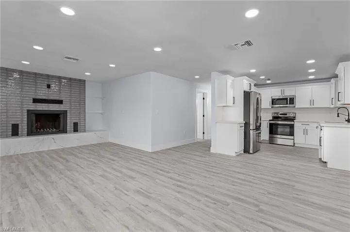 Unfurnished living room with recessed lighting, light wood-style flooring, and a brick fireplace