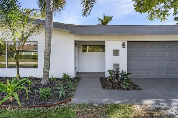Property entrance featuring stucco siding, an attached garage, and driveway