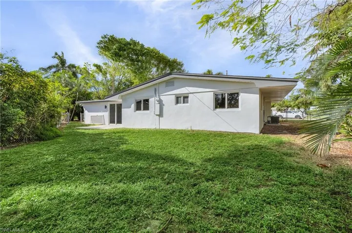 Back of house with stucco siding and a yard