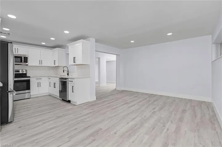 Kitchen featuring appliances with stainless steel finishes, light countertops, light wood-type flooring, white cabinetry, and recessed lighting